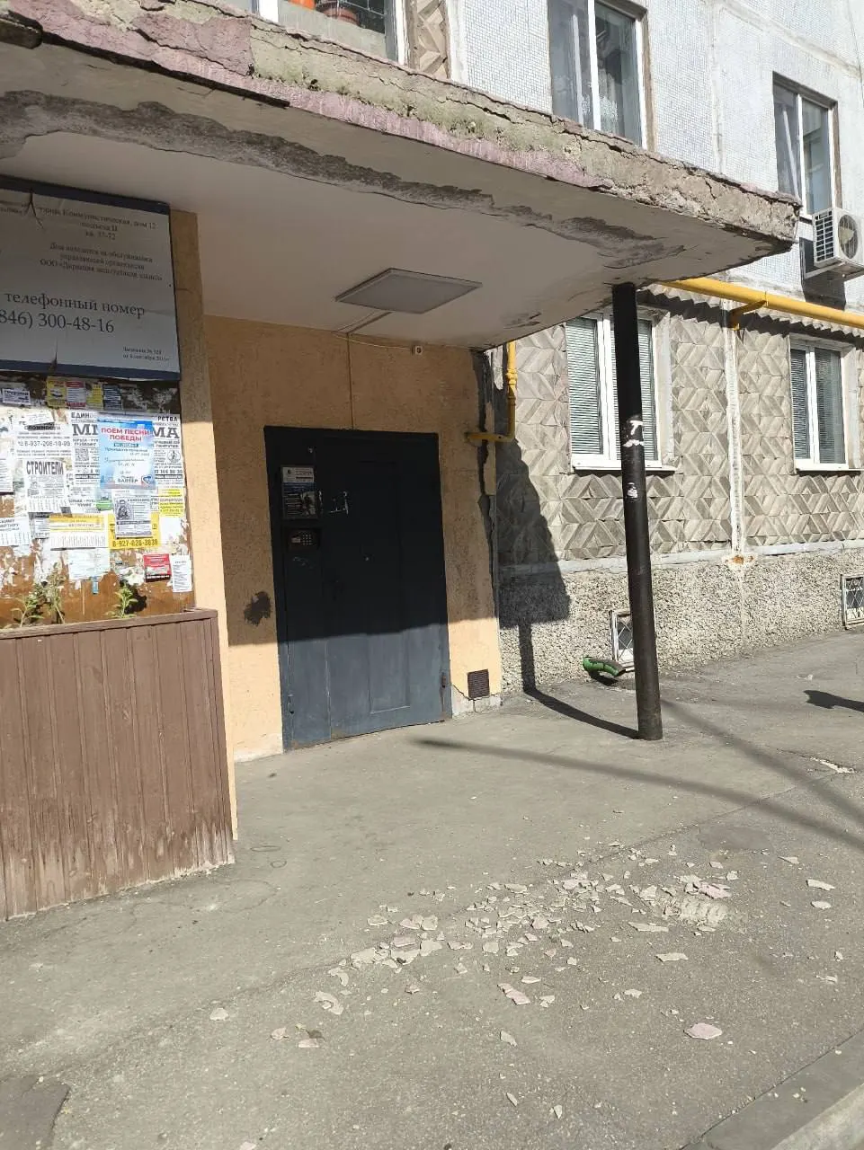 Жители дома на Коммунистической, 12 жалуются, что обломки с козырька над входом регулярно сыплются на прохожих, а управляющая компания не устраняет проблему уже четыре года.