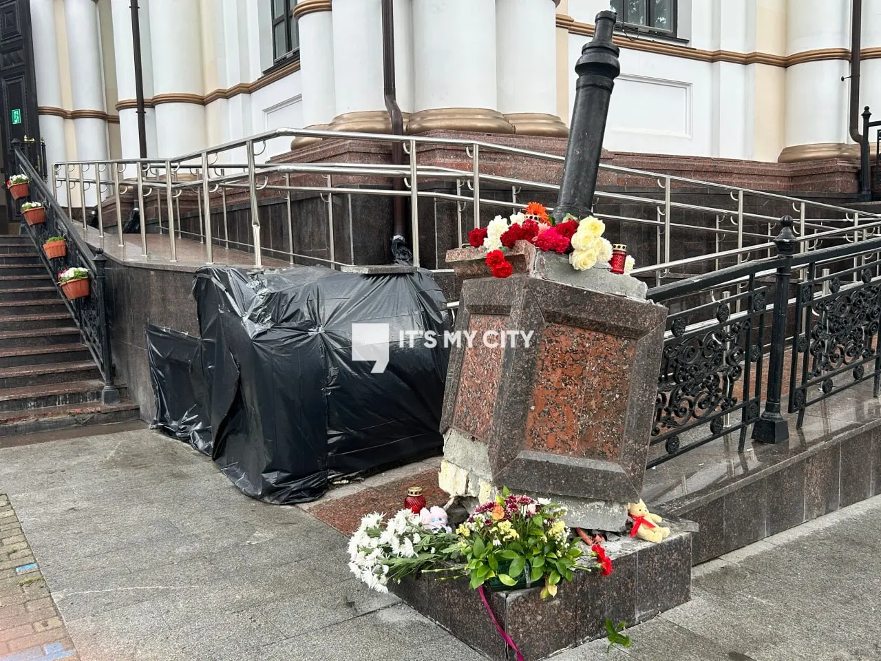 Жители приносят цветы и игрушки в память о четырех погибших в аварии с автобусом. На перекрестке не работает светофор, рабочие восстанавливают ограждение и приводят в порядок клумбу, снесённые автобусом.