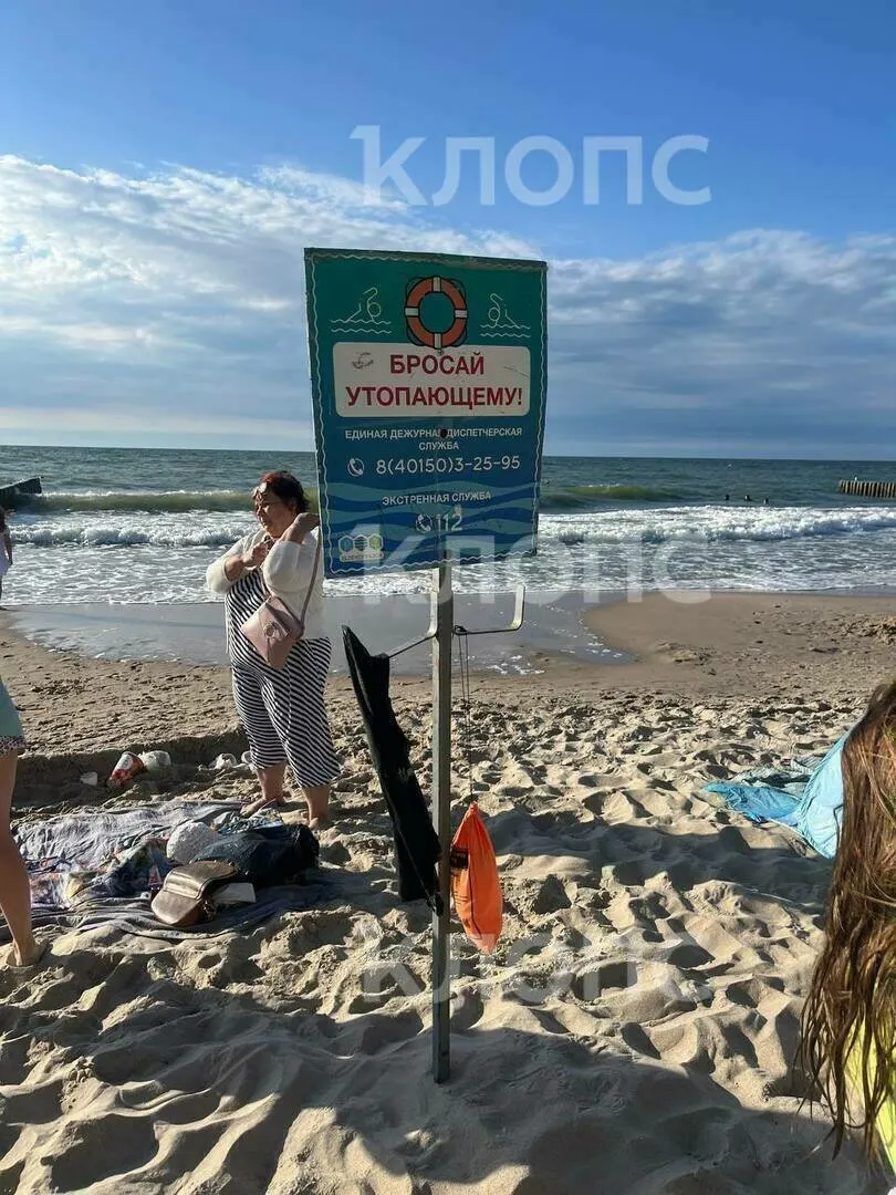 На городском пляже Зеленоградска отец двоих детей бросился спасать тонущую девочку при сильном волнении; очевидцы вытащили его на берег, спасатели подошли позднее.