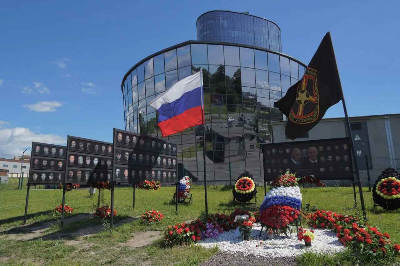 В годовщину мятежа к стенду памяти Евгения Пригожина положили искусственную лилию; фотографии на мемориале заменили — теперь они напечатаны на самих стендах.