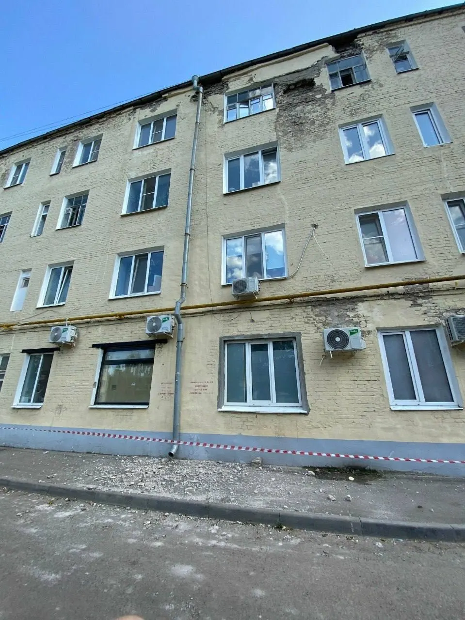 Управляющая компания оградила участок лентой, но в дождь единственный сухой путь домой проходит прямо под падающими кусками бетона; другие проходы залиты водой по щиколотку.