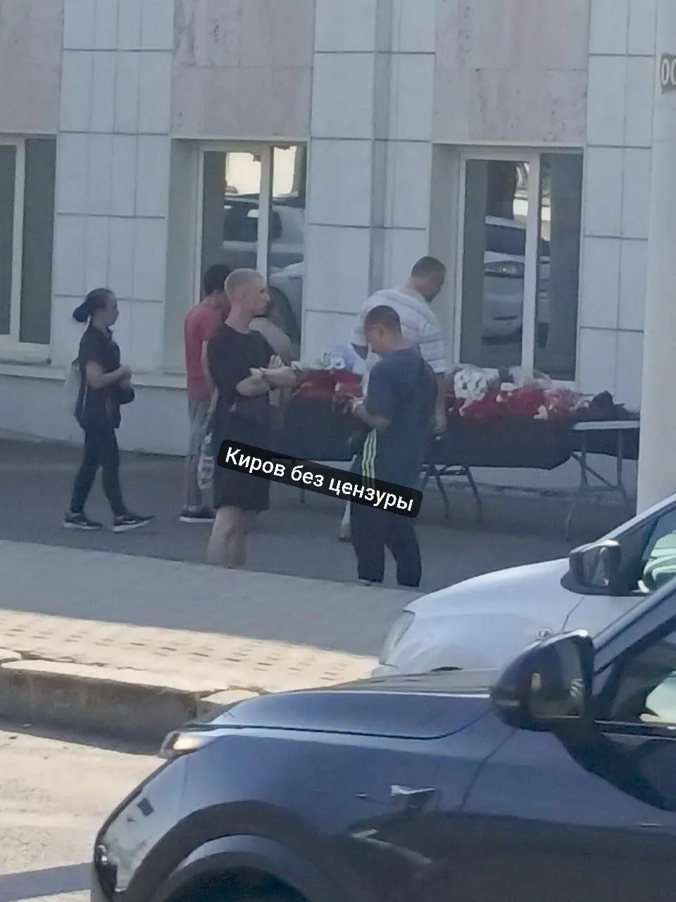 Жители города несут цветы к входу предприятия, пострадавшего в результате ракетного удара, чтобы почтить память погибших.