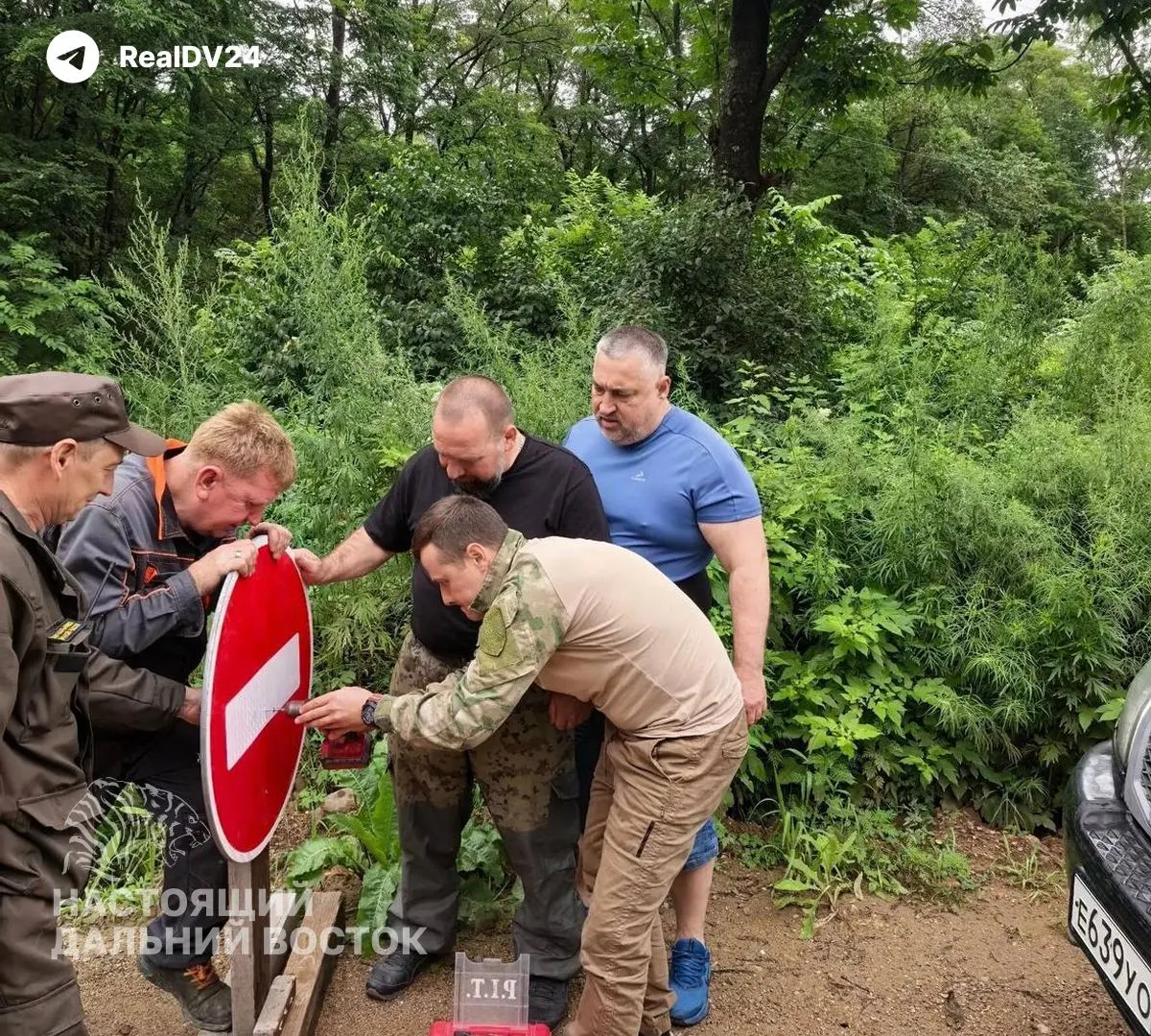 Четыре работника устанавливают дорожный знак возле аварийного моста в Партизанском районе. Официальных данных об ограничениях движения на участке пока нет.