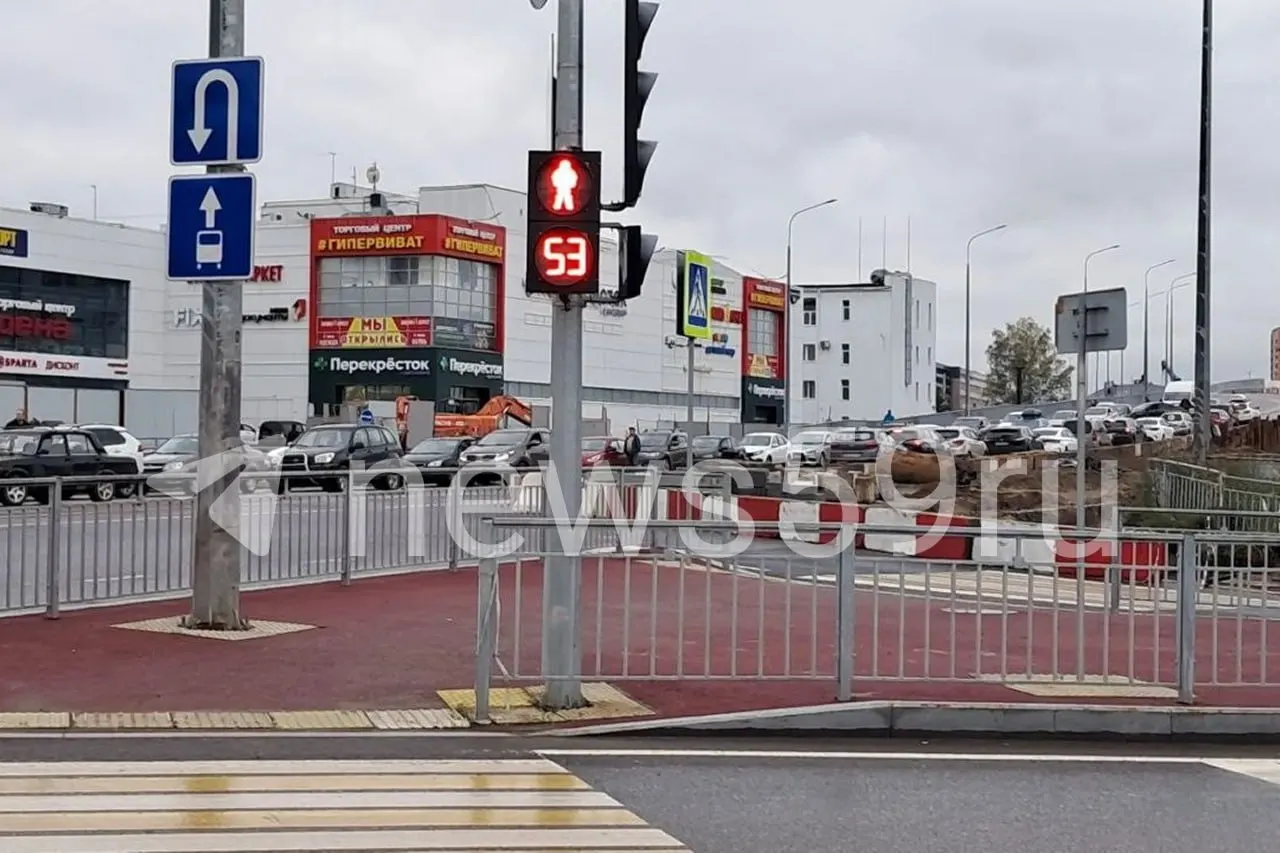 Длинные очереди автомобилей у заправки перед выставочным центром, автобусы разворачиваются на перекрёстке.