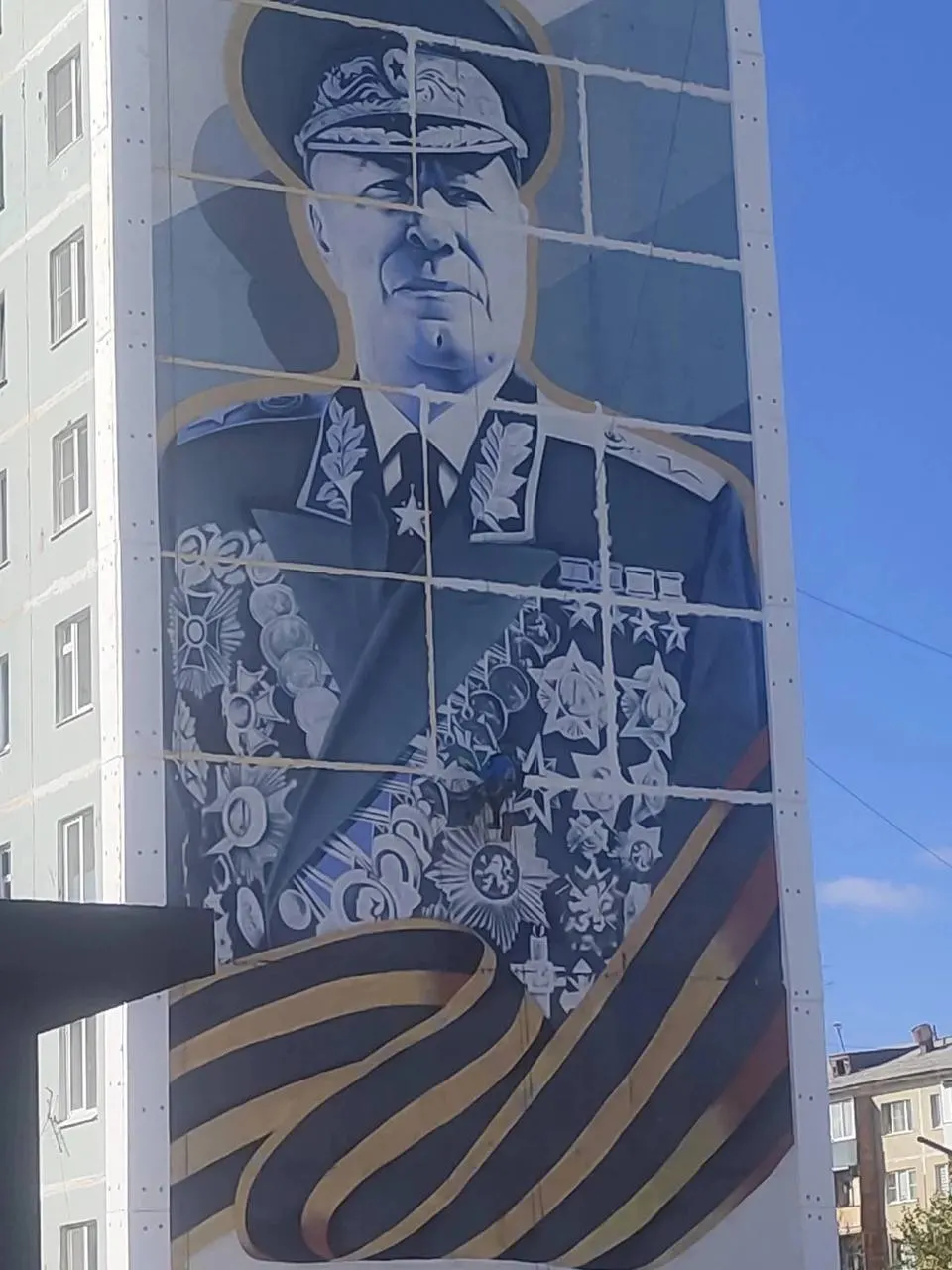 После утепления швов на мурале маршала Жукова на фасаде дома появились светлые полосы; жильцы говорят, что рисунок выглядит как за решёткой и требует восстановления весной.